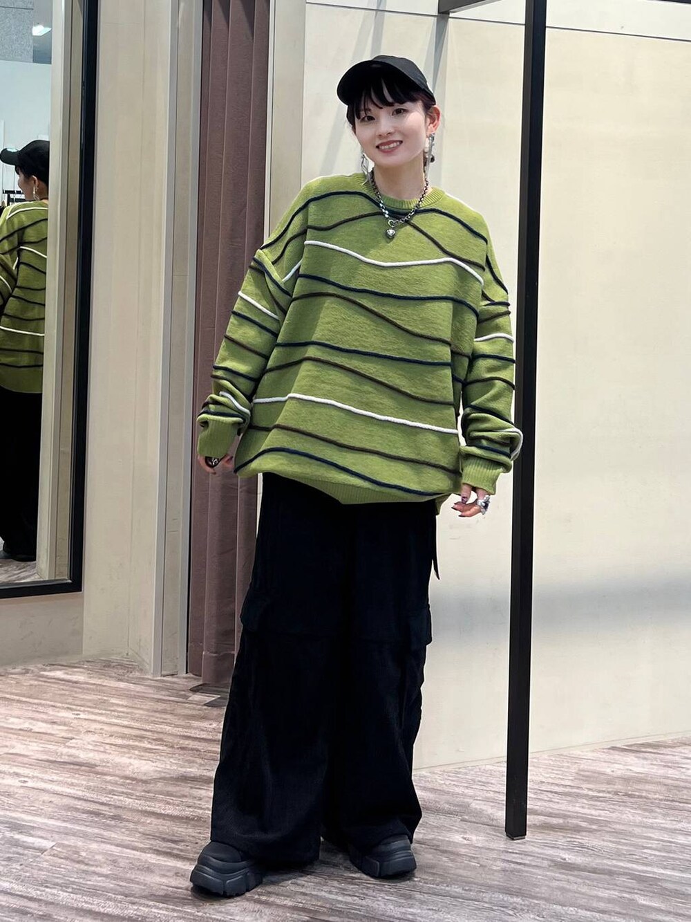 ブラック系のカーゴパンツ、グリーン系のニット/セーター、ブラック系のブーツを着用したレディースの冬コーディネートの2枚目の写真