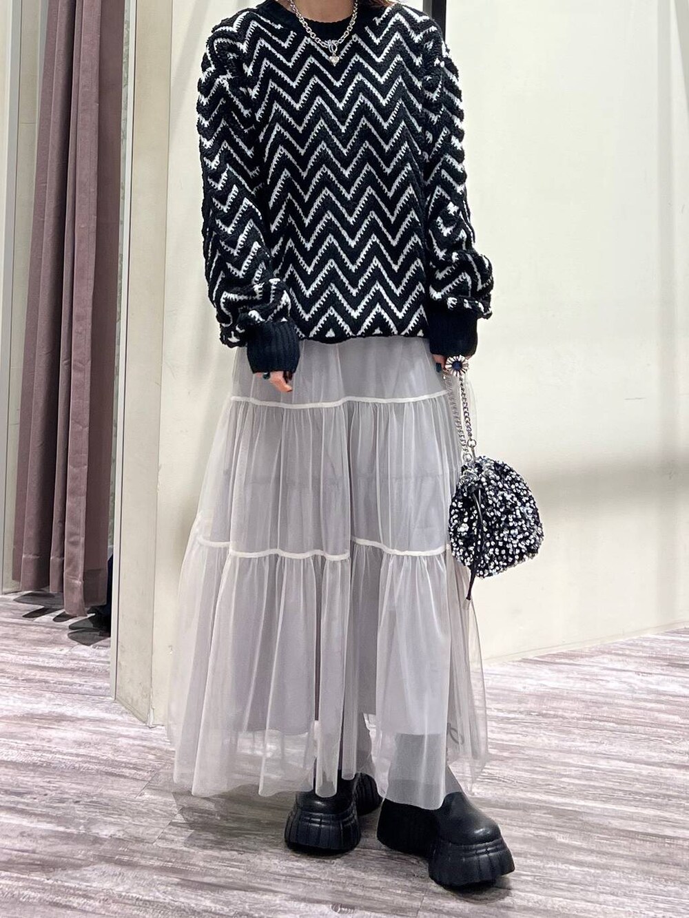 ブラック系のブーツ、シルバー系のショルダーバッグ、ブラック系のニット/セーターを着用したレディースの冬コーディネートの6枚目の写真