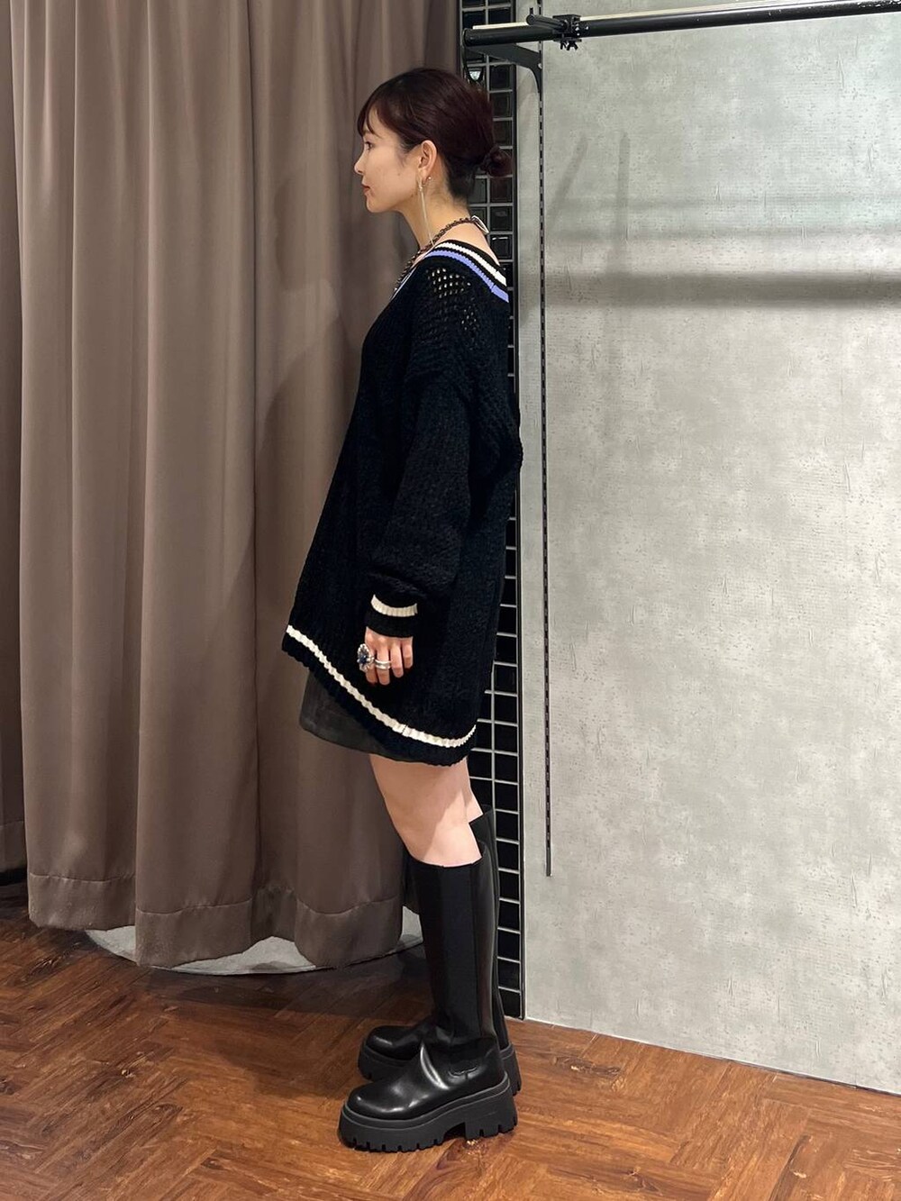 ブラック系のニット/セーター、ブラック系のスカート、ブラック系のブーツを着用したレディースの秋コーディネートの3枚目の写真
