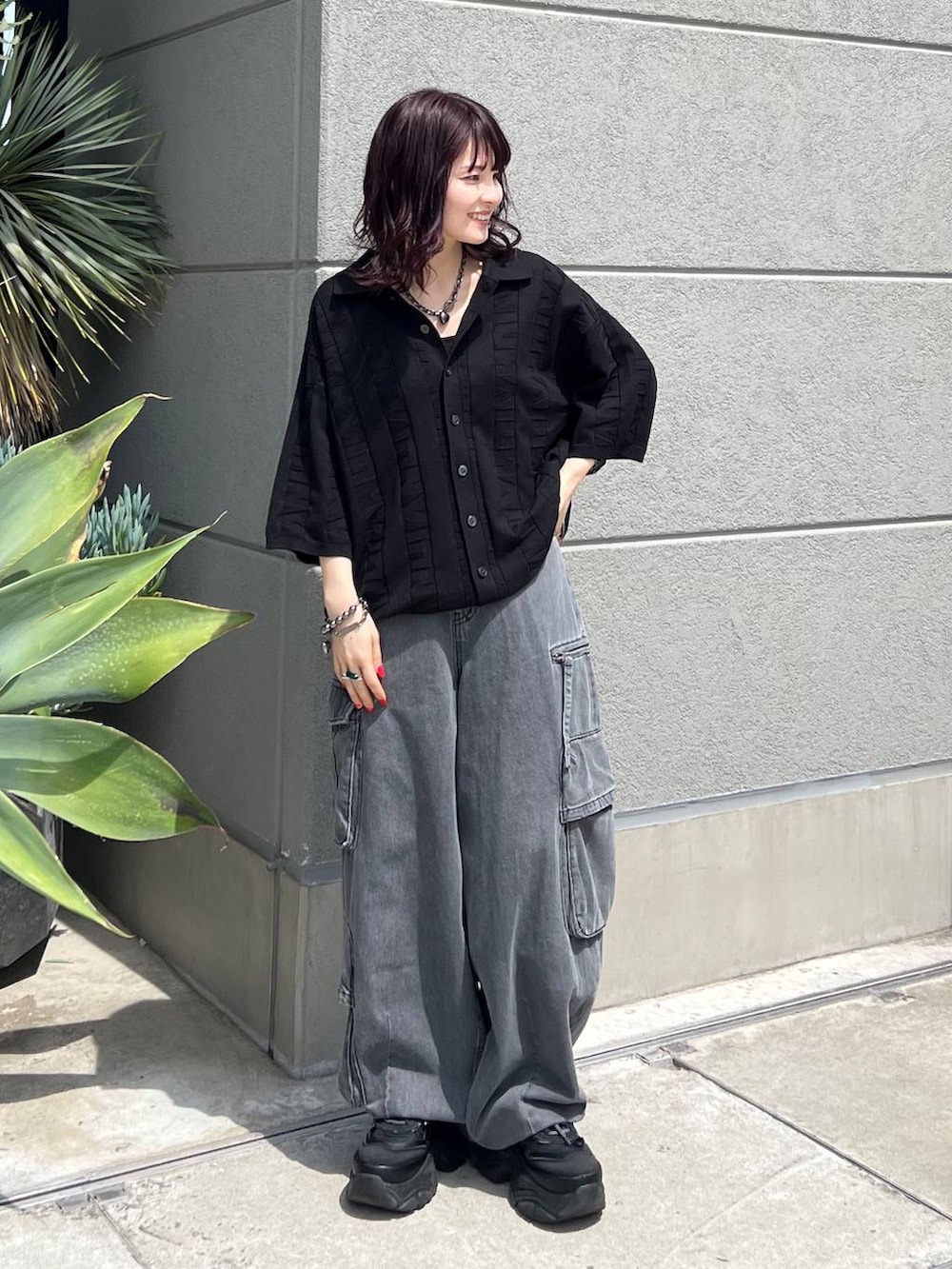 ブラック系のニット/セーター、ブラック系のスニーカー、ブラック系のデニムパンツを着用したレディースの夏コーディネートの7枚目の写真