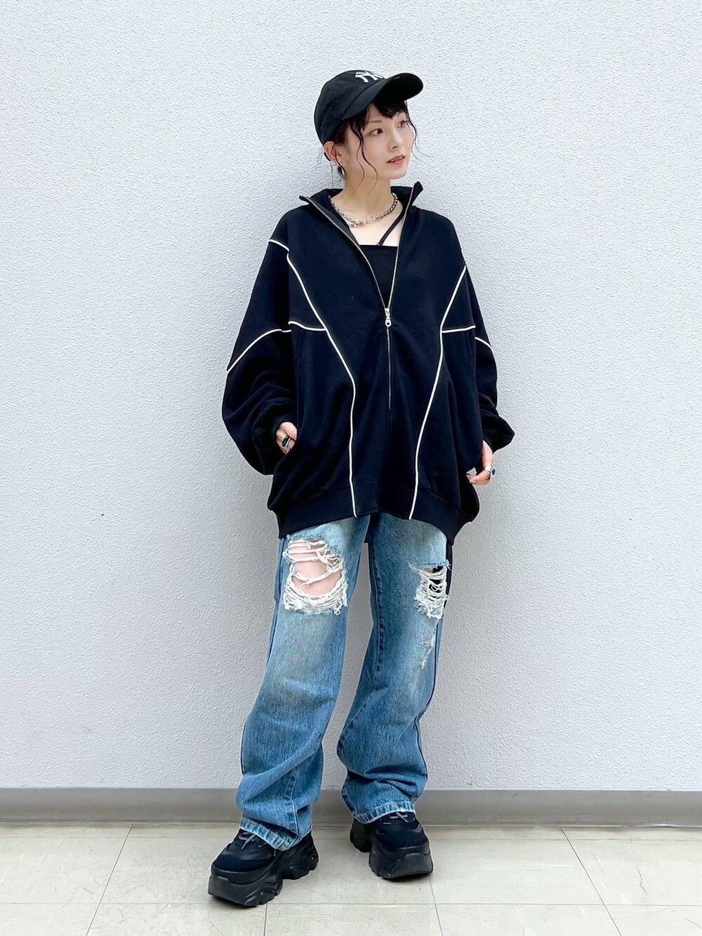 ブラック系のキャミソール、ブルー系のデニムパンツ、ブラック系のスニーカーを着用したレディースの春コーディネートの2枚目の写真