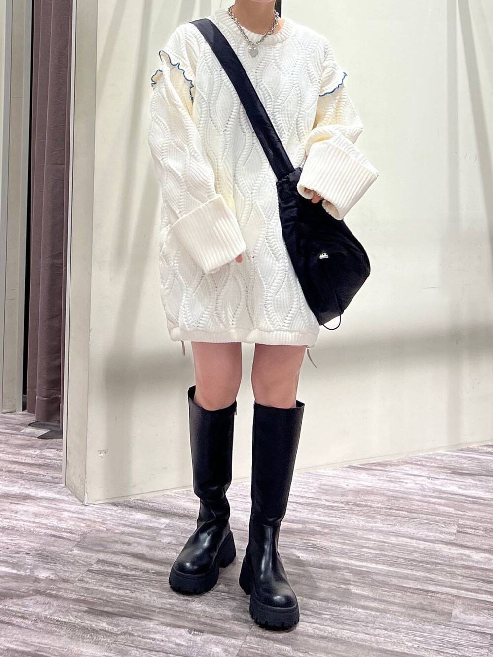 ブラック系のブーツ、ブラック系のショルダーバッグ、ホワイト系のニット/セーターを着用したレディースの冬コーディネートの6枚目の写真