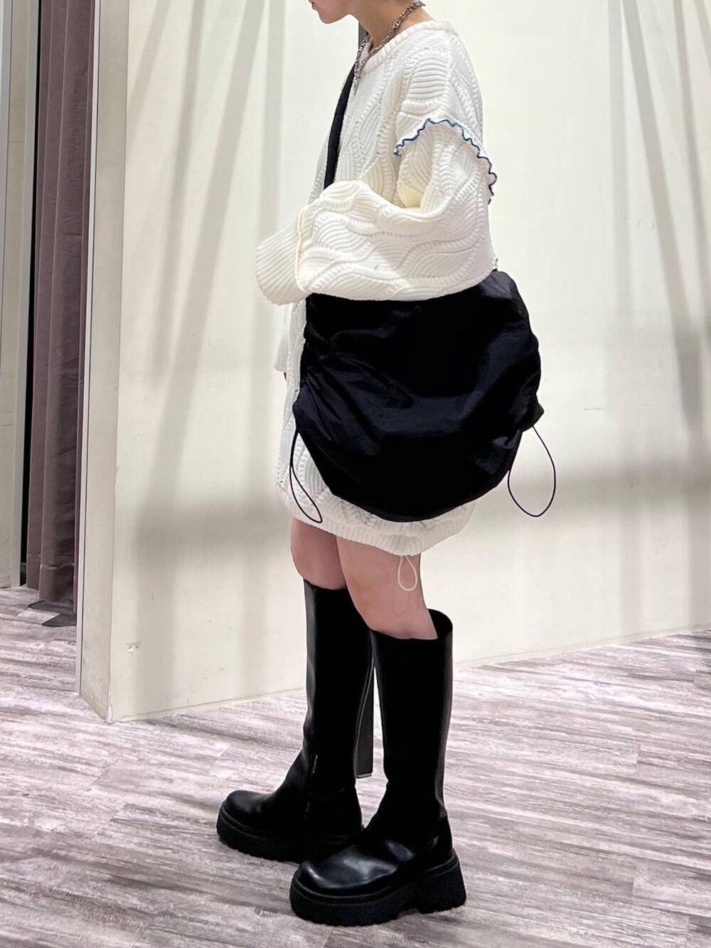 ブラック系のブーツ、ブラック系のショルダーバッグ、ホワイト系のニット/セーターを着用したレディースの冬コーディネートの5枚目の写真