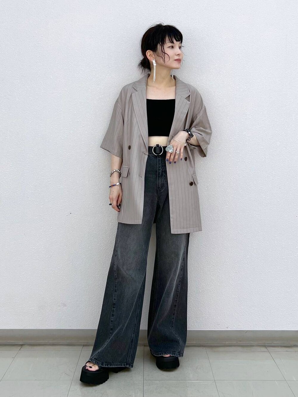 ブラック系のデニムパンツ、ブラック系のサンダル、ブラウン系のテーラードジャケットを着用したレディースの秋コーディネートの2枚目の写真