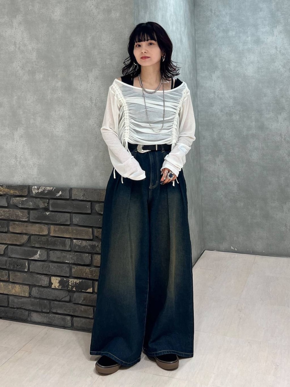 ブルー系のデニムパンツ、ブラック系のタンクトップ、ホワイト系のTシャツ/カットソーを着用したレディースの春コーディネートの2枚目の写真