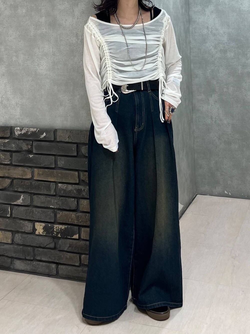 ブルー系のデニムパンツ、ブラック系のタンクトップ、ホワイト系のTシャツ/カットソーを着用したレディースの春コーディネートの6枚目の写真