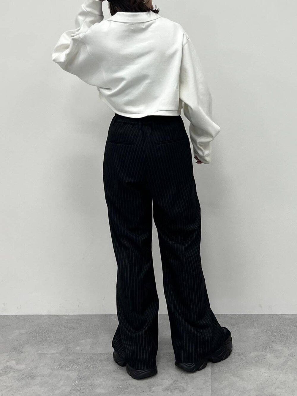 ブラック系のキャミソール、ブラック系のスラックス、ブラック系のスニーカーを着用したレディースの冬コーディネートの3枚目の写真