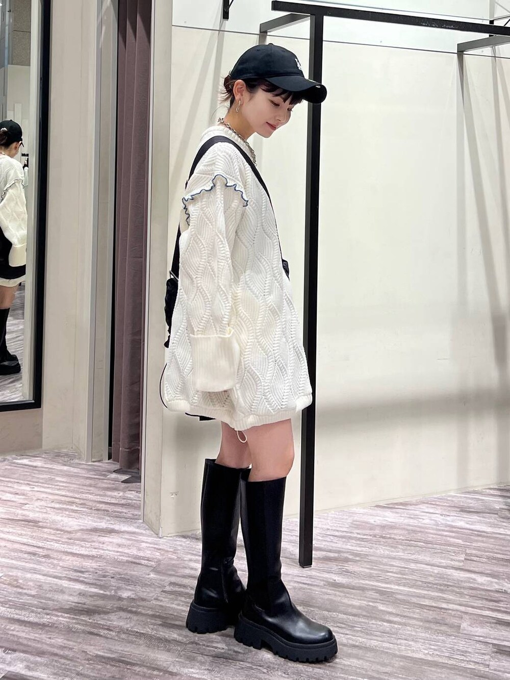 ブラック系のブーツ、ブラック系のショルダーバッグ、ホワイト系のニット/セーターを着用したレディースの冬コーディネートの2枚目の写真