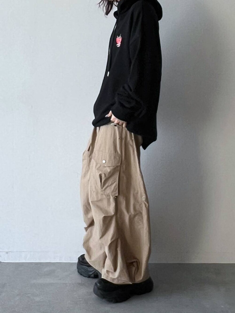 ブラック系のスニーカー、ベージュ系のカーゴパンツ、ブラック系のパーカーを着用したレディースの夏コーディネートの3枚目の写真