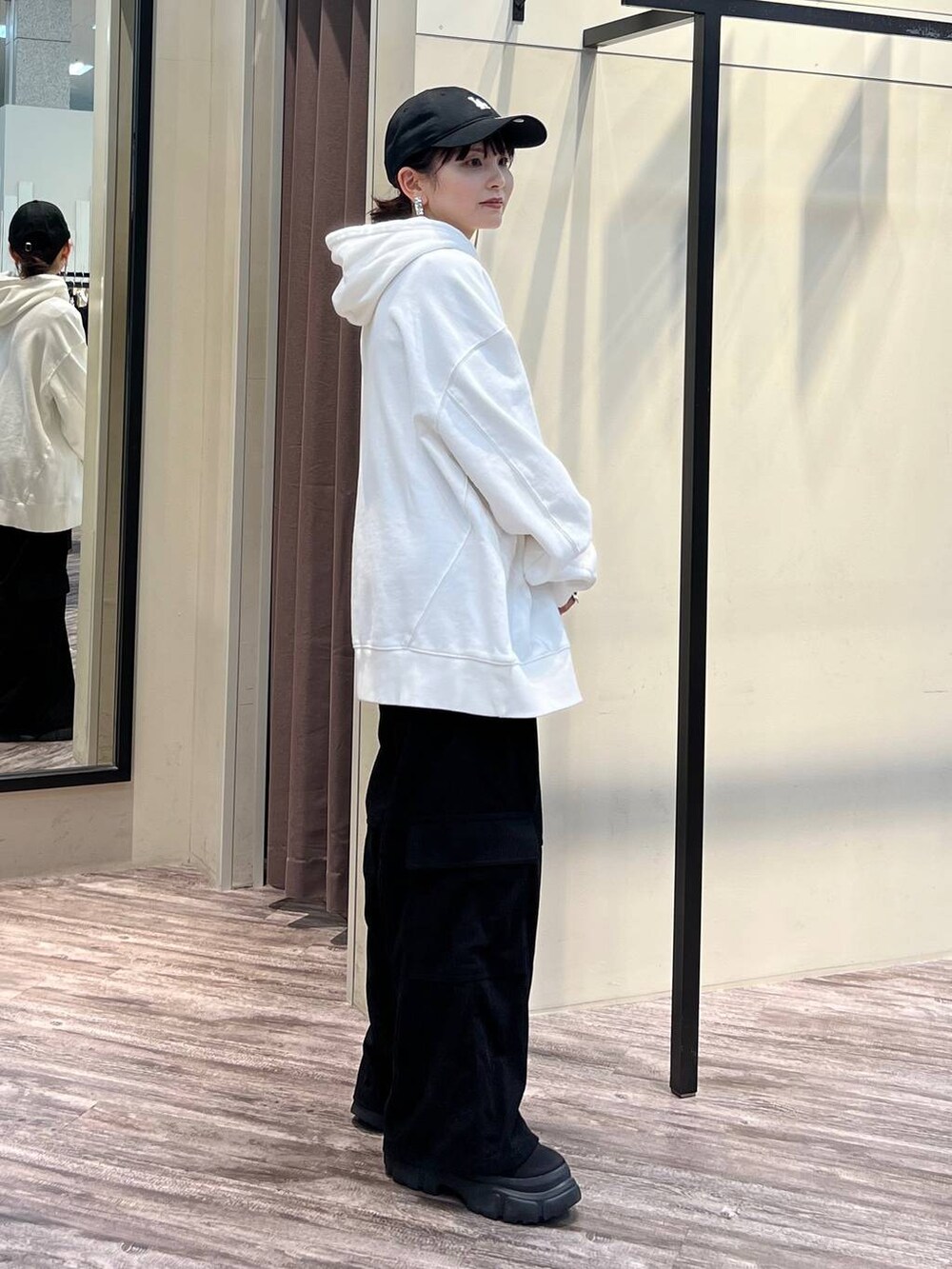 ブラック系のカーゴパンツ、ブラック系のブーツ、ホワイト系のパーカーを着用したレディースの冬コーディネートの4枚目の写真