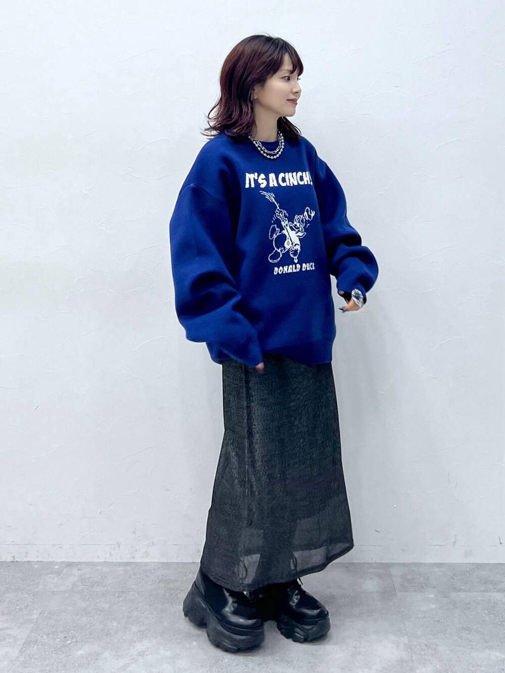 ブラック系のブーツ、ブラック系のスカート、ブルー系のニット/セーターを着用したレディースの冬コーディネートの3枚目の写真