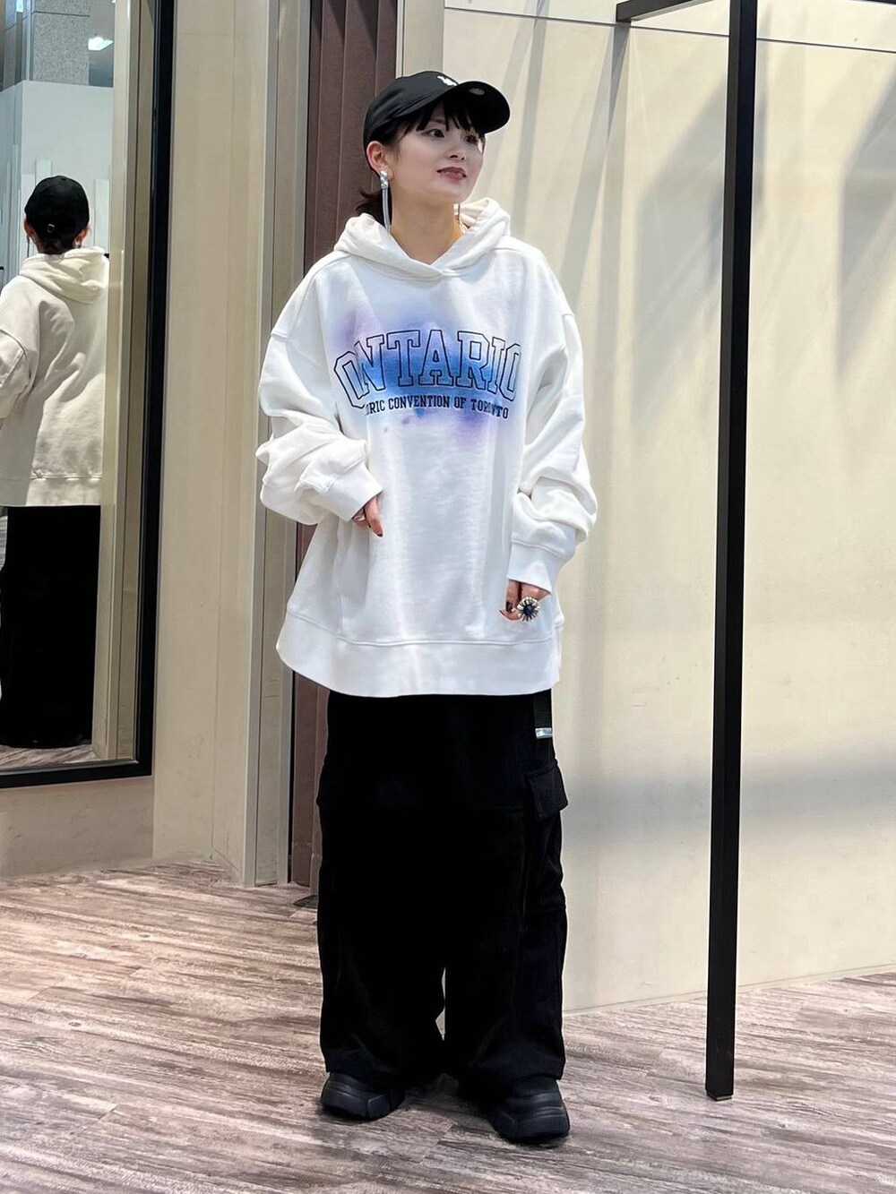 ブラック系のカーゴパンツ、ブラック系のブーツ、ホワイト系のパーカーを着用したレディースの冬コーディネートの2枚目の写真