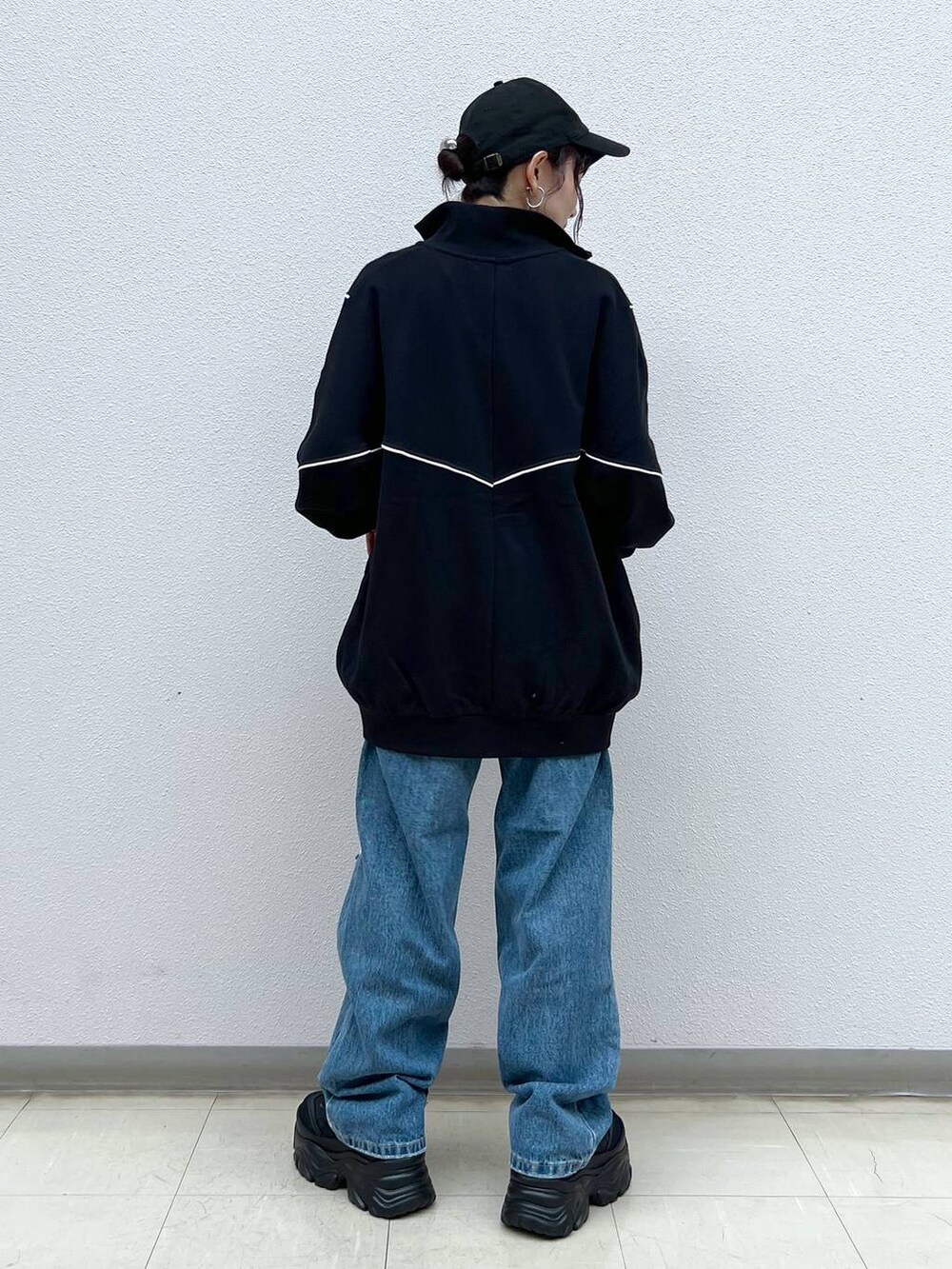 ブラック系のキャミソール、ブルー系のデニムパンツ、ブラック系のスニーカーを着用したレディースの春コーディネートの5枚目の写真