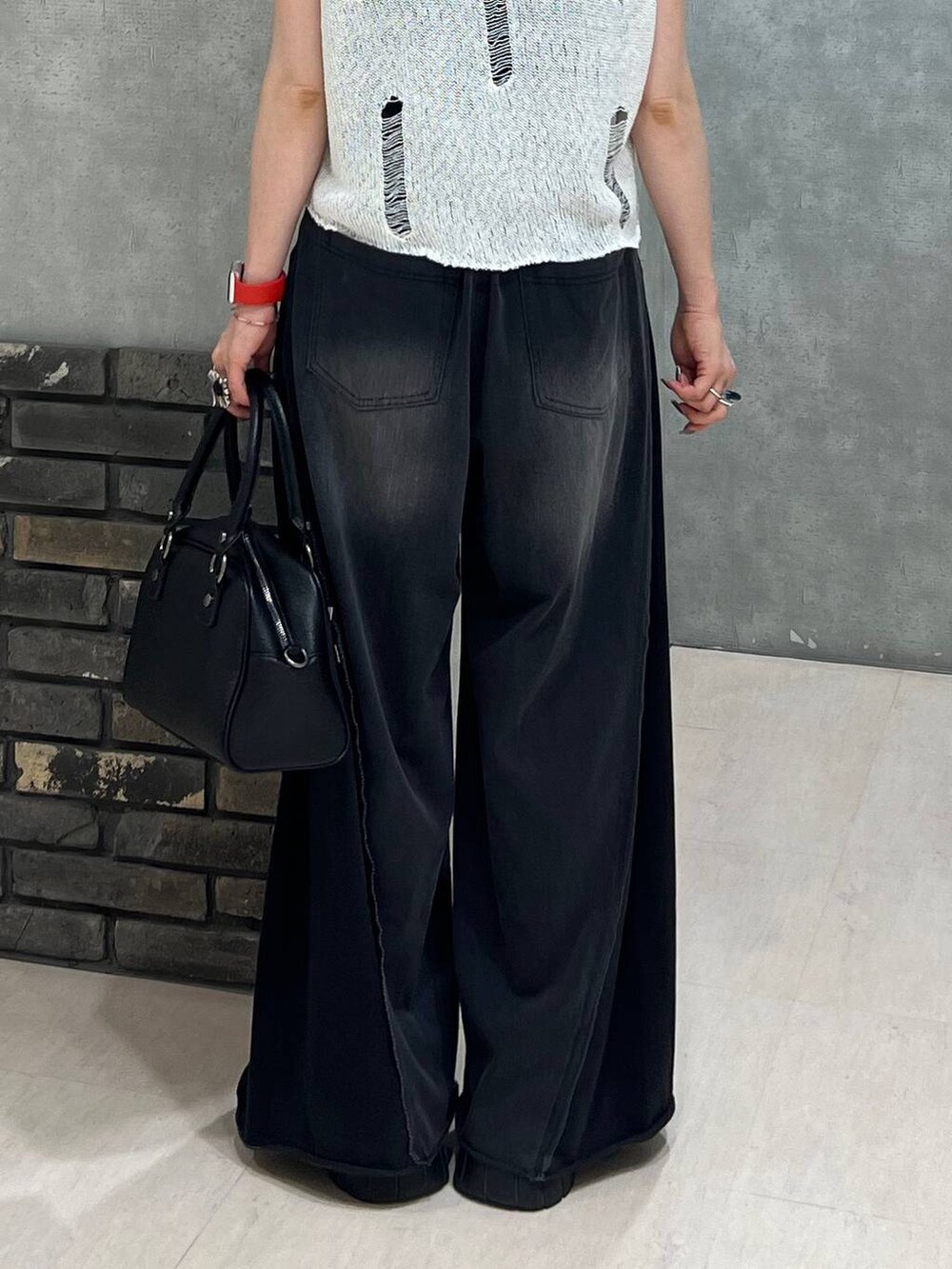 ブラック系のデニムパンツ、ブラック系のショルダーバッグ、ホワイト系のベストを着用したレディースの夏コーディネートの4枚目の写真