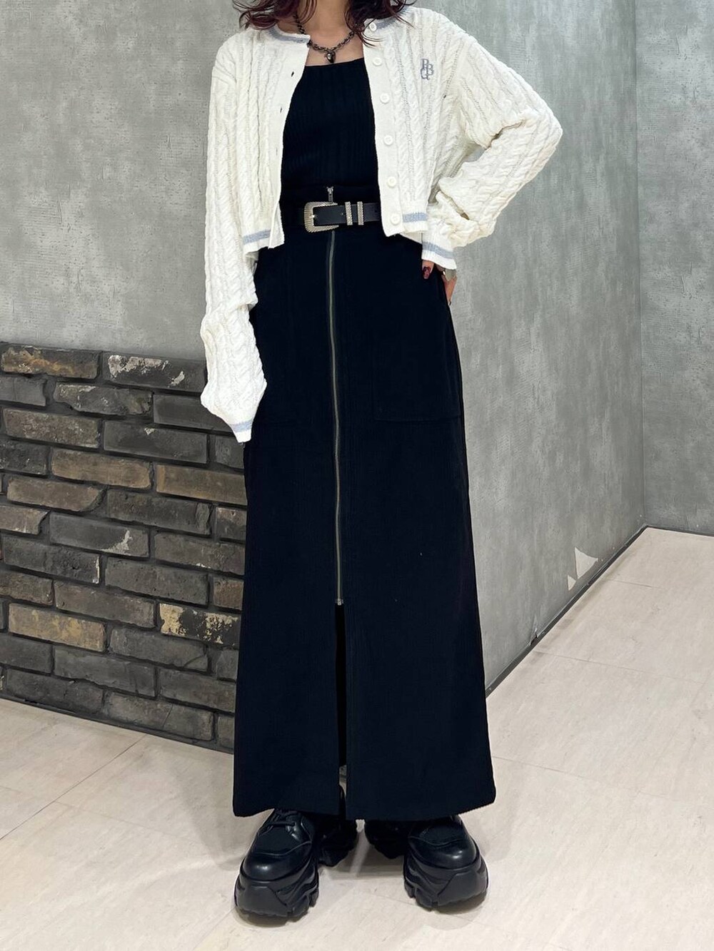 ブラック系のブーツ、ブラック系のスカート、ホワイト系のカーディガン/ボレロを着用したレディースの冬コーディネートの6枚目の写真