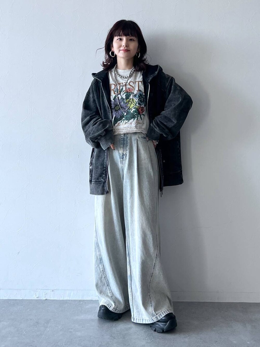 ブラック系のスニーカー、ブルー系のデニムパンツ、ベージュ系のTシャツ/カットソーを着用したレディースの秋コーディネートの2枚目の写真