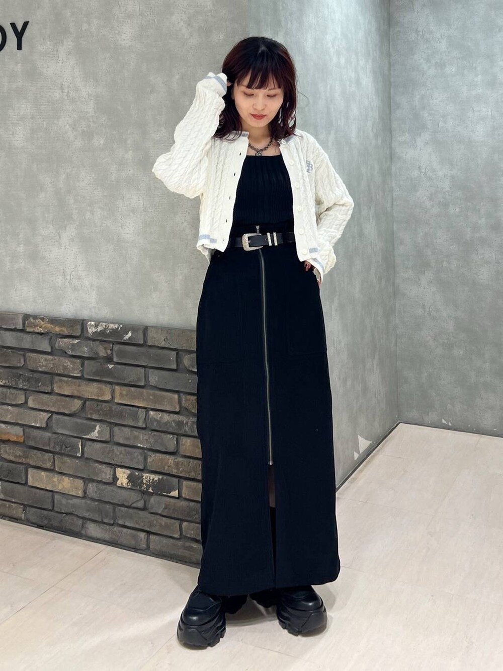 ブラック系のブーツ、ブラック系のスカート、ホワイト系のカーディガン/ボレロを着用したレディースの冬コーディネートの2枚目の写真