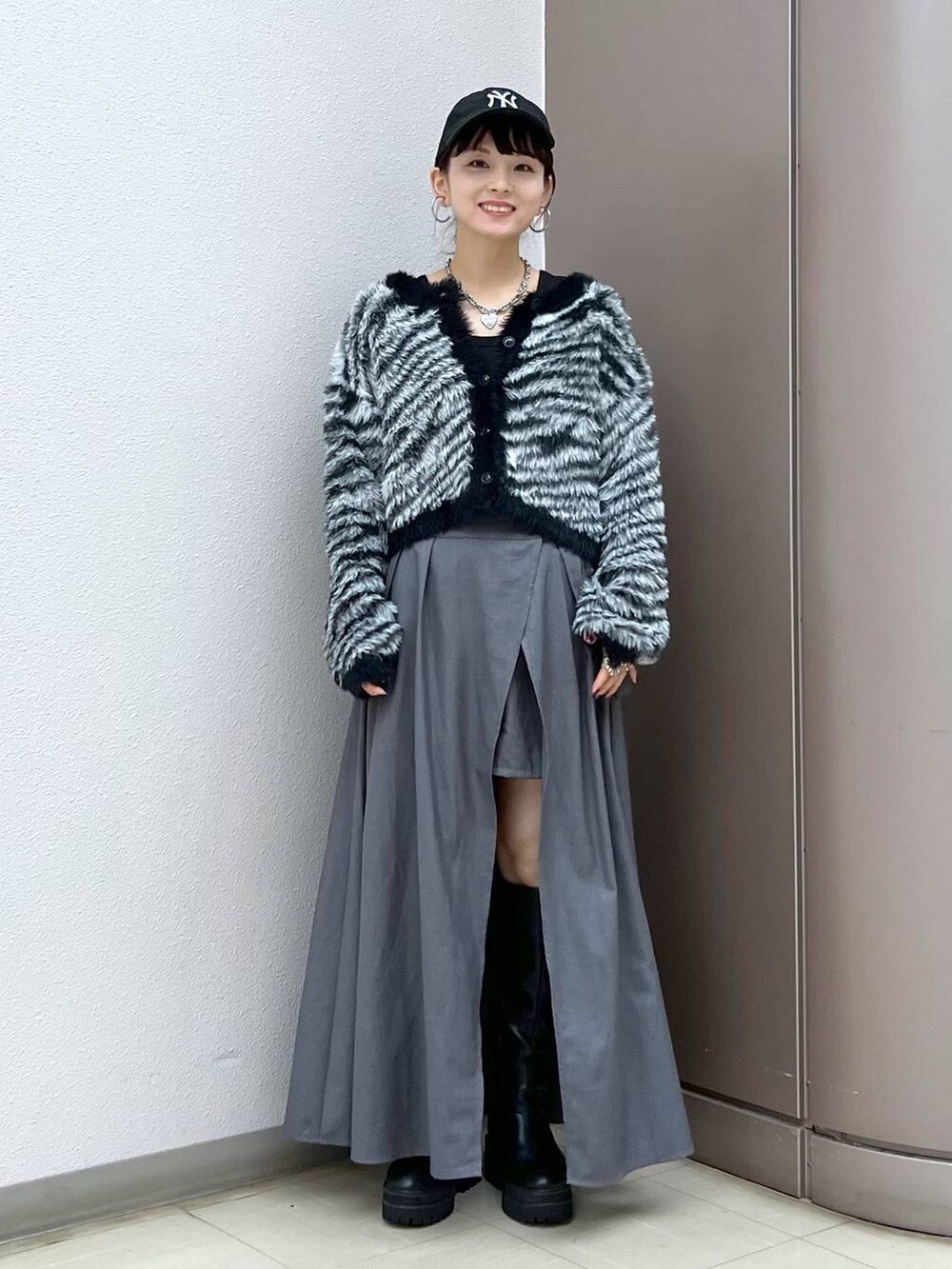 ブラック系のブーツ、グレー系のスカート、その他のカーディガン/ボレロを着用したレディースの秋コーディネートの2枚目の写真