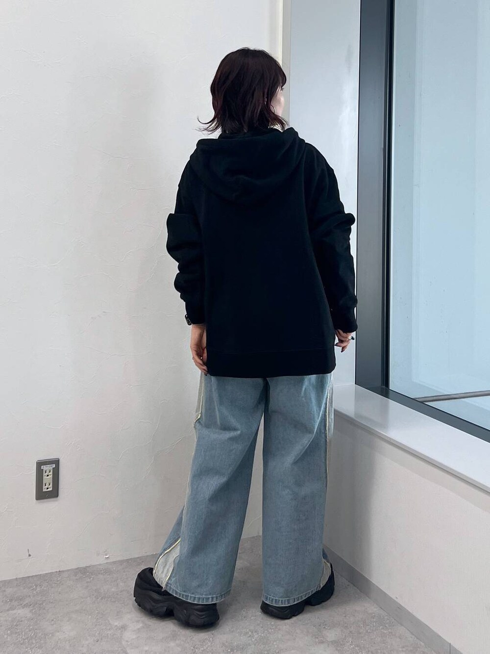 ブラック系のパーカー、ブラック系のスニーカー、ブルー系のデニムパンツを着用したレディースの冬コーディネートの4枚目の写真