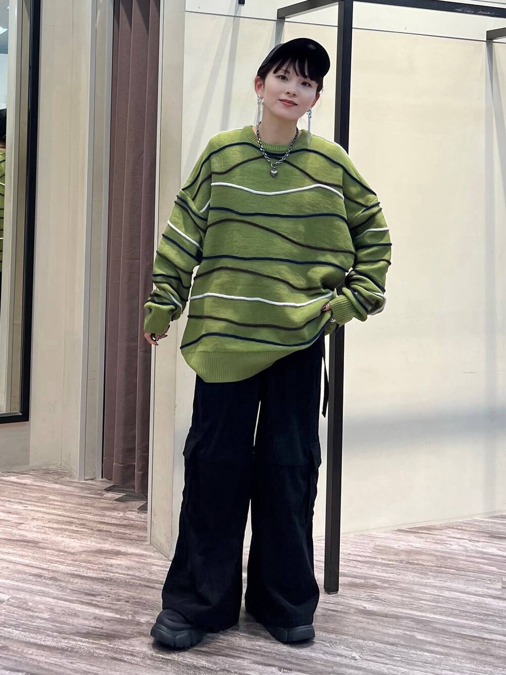 ブラック系のカーゴパンツ、グリーン系のニット/セーター、ブラック系のブーツを着用したレディースの冬コーディネートの7枚目の写真