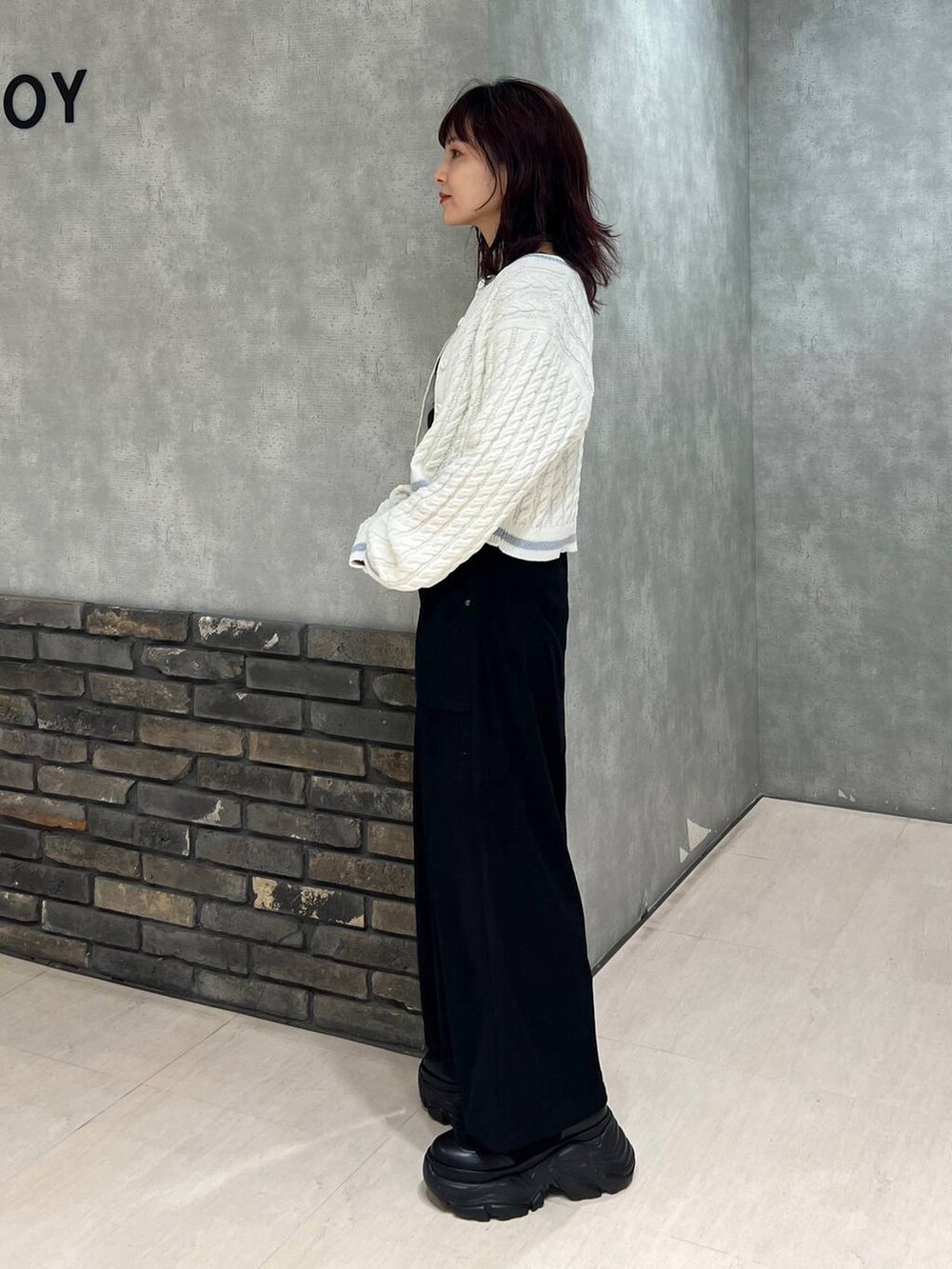 ブラック系のブーツ、ブラック系のスカート、ホワイト系のカーディガン/ボレロを着用したレディースの冬コーディネートの3枚目の写真