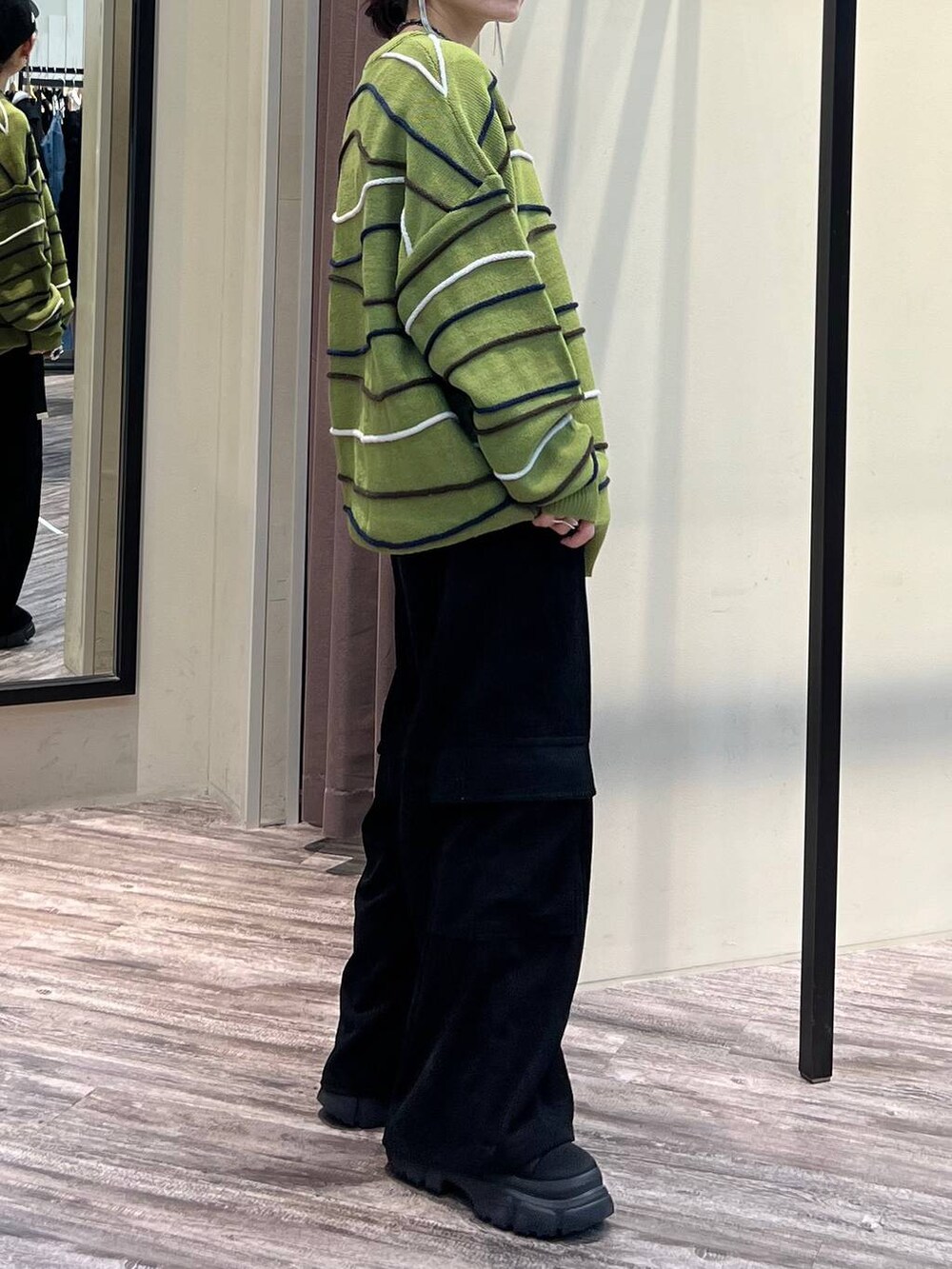 ブラック系のカーゴパンツ、グリーン系のニット/セーター、ブラック系のブーツを着用したレディースの冬コーディネートの4枚目の写真