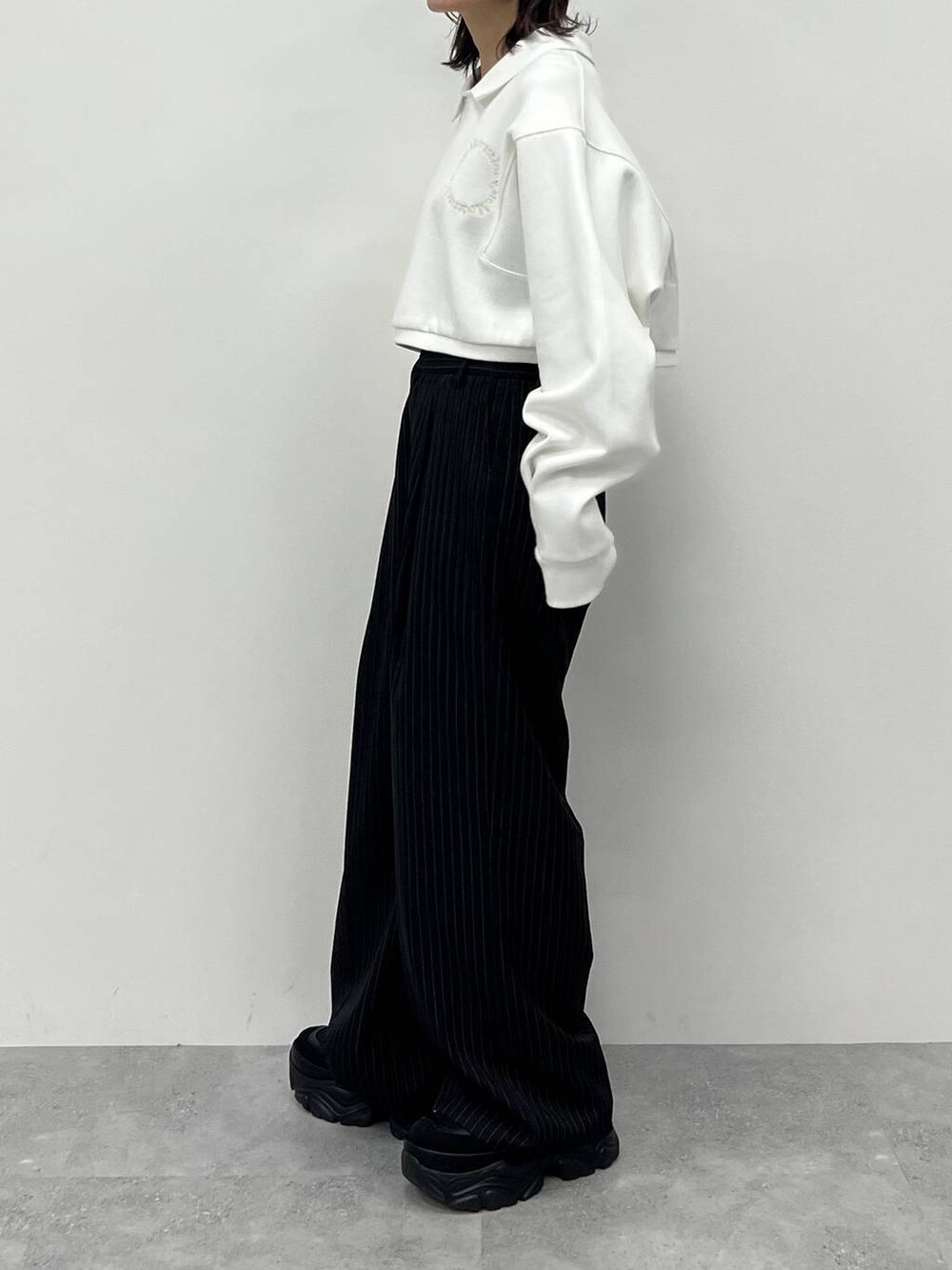 ブラック系のキャミソール、ブラック系のスラックス、ブラック系のスニーカーを着用したレディースの冬コーディネートの4枚目の写真