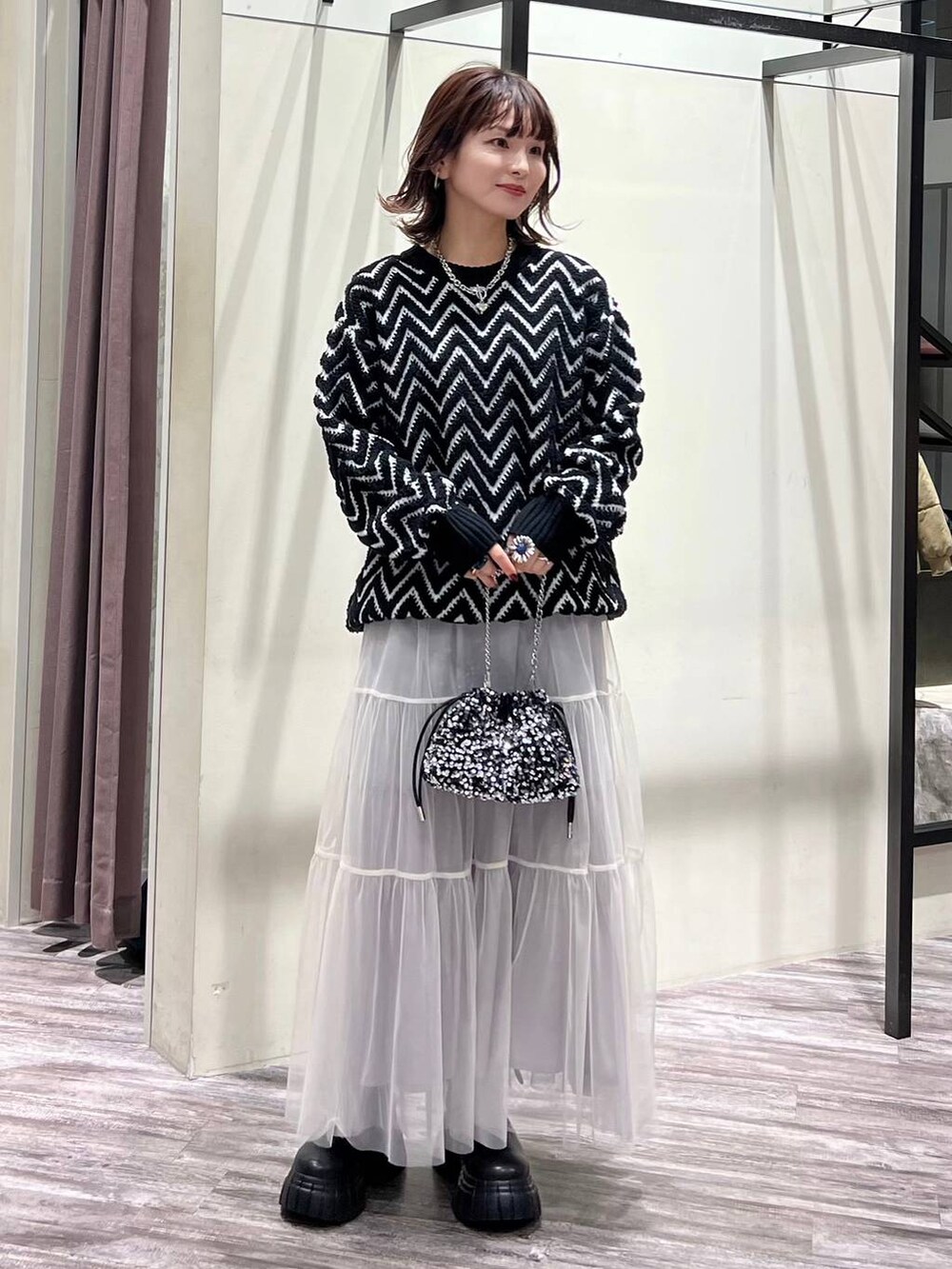 ブラック系のブーツ、シルバー系のショルダーバッグ、ブラック系のニット/セーターを着用したレディースの冬コーディネートの2枚目の写真