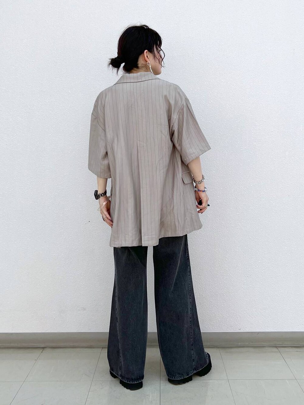 ブラック系のデニムパンツ、ブラック系のサンダル、ブラウン系のテーラードジャケットを着用したレディースの秋コーディネートの4枚目の写真