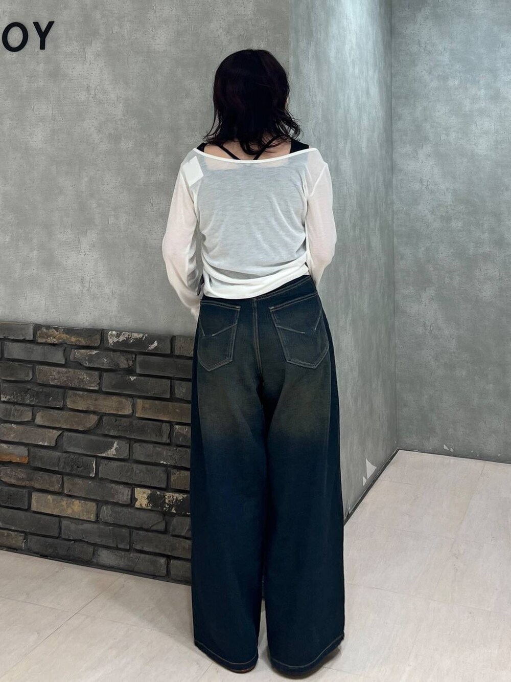 ブルー系のデニムパンツ、ブラック系のタンクトップ、ホワイト系のTシャツ/カットソーを着用したレディースの春コーディネートの4枚目の写真