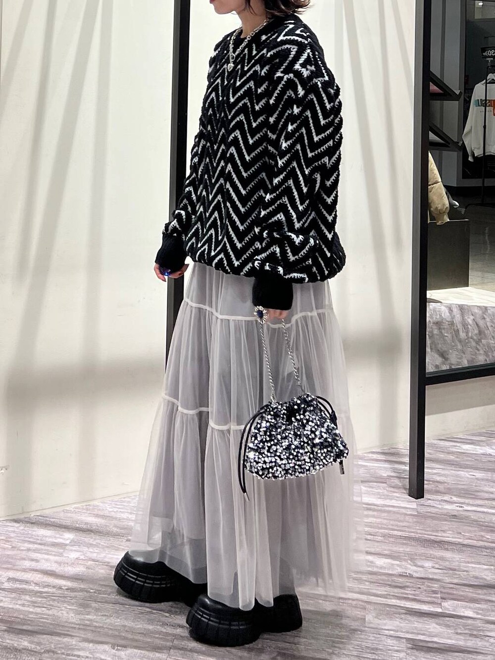 ブラック系のブーツ、シルバー系のショルダーバッグ、ブラック系のニット/セーターを着用したレディースの冬コーディネートの5枚目の写真