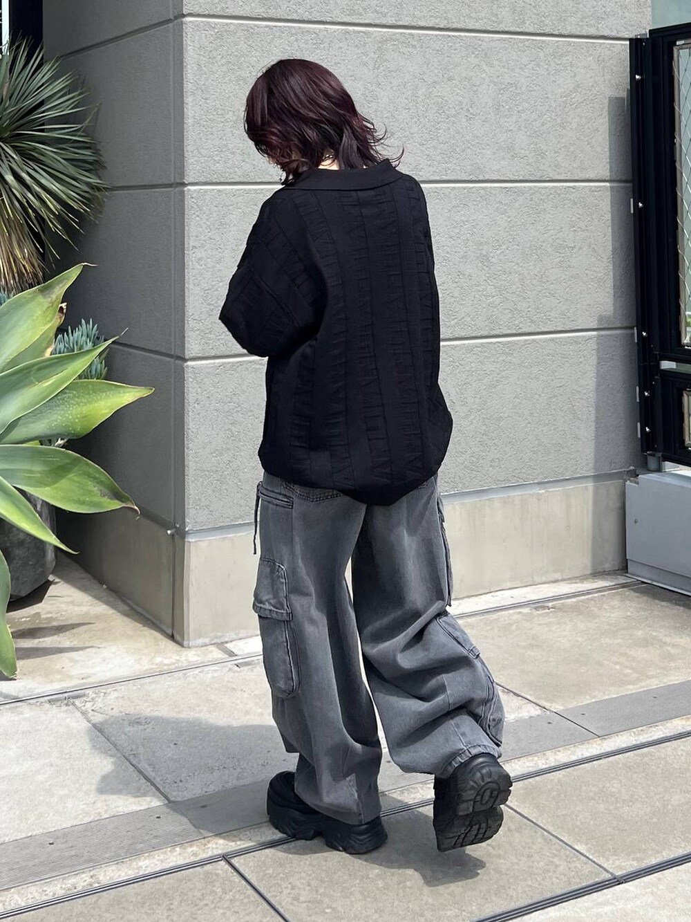 ブラック系のニット/セーター、ブラック系のスニーカー、ブラック系のデニムパンツを着用したレディースの夏コーディネートの4枚目の写真