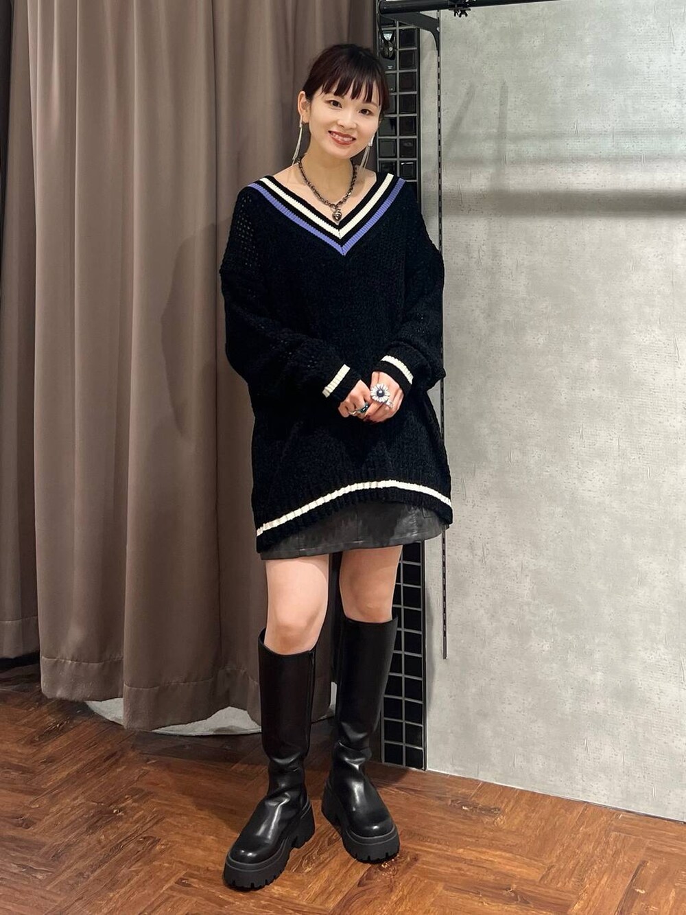ブラック系のニット/セーター、ブラック系のスカート、ブラック系のブーツを着用したレディースの秋コーディネートの7枚目の写真
