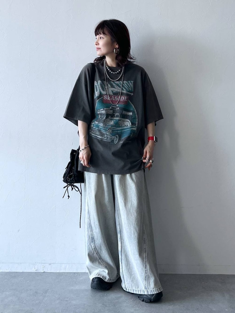 ブラック系のスニーカー、ブルー系のデニムパンツ、グレー系のTシャツ/カットソーを着用したレディースの夏コーディネートの2枚目の写真