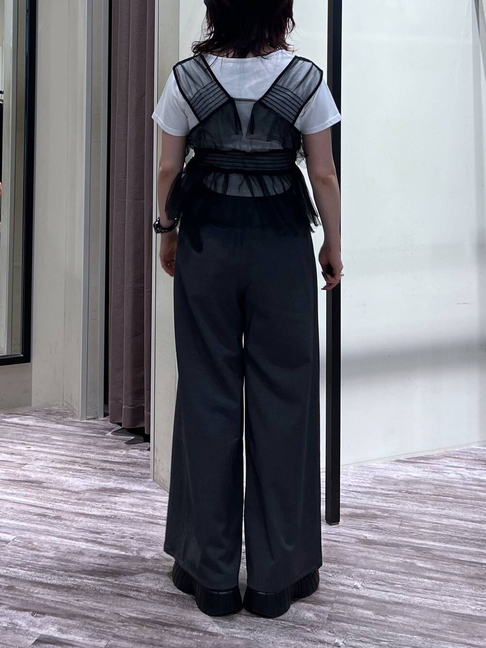 ブラック系のスニーカー、グレー系のスラックス、ブラック系のベストを着用したレディースの夏コーディネートの5枚目の写真