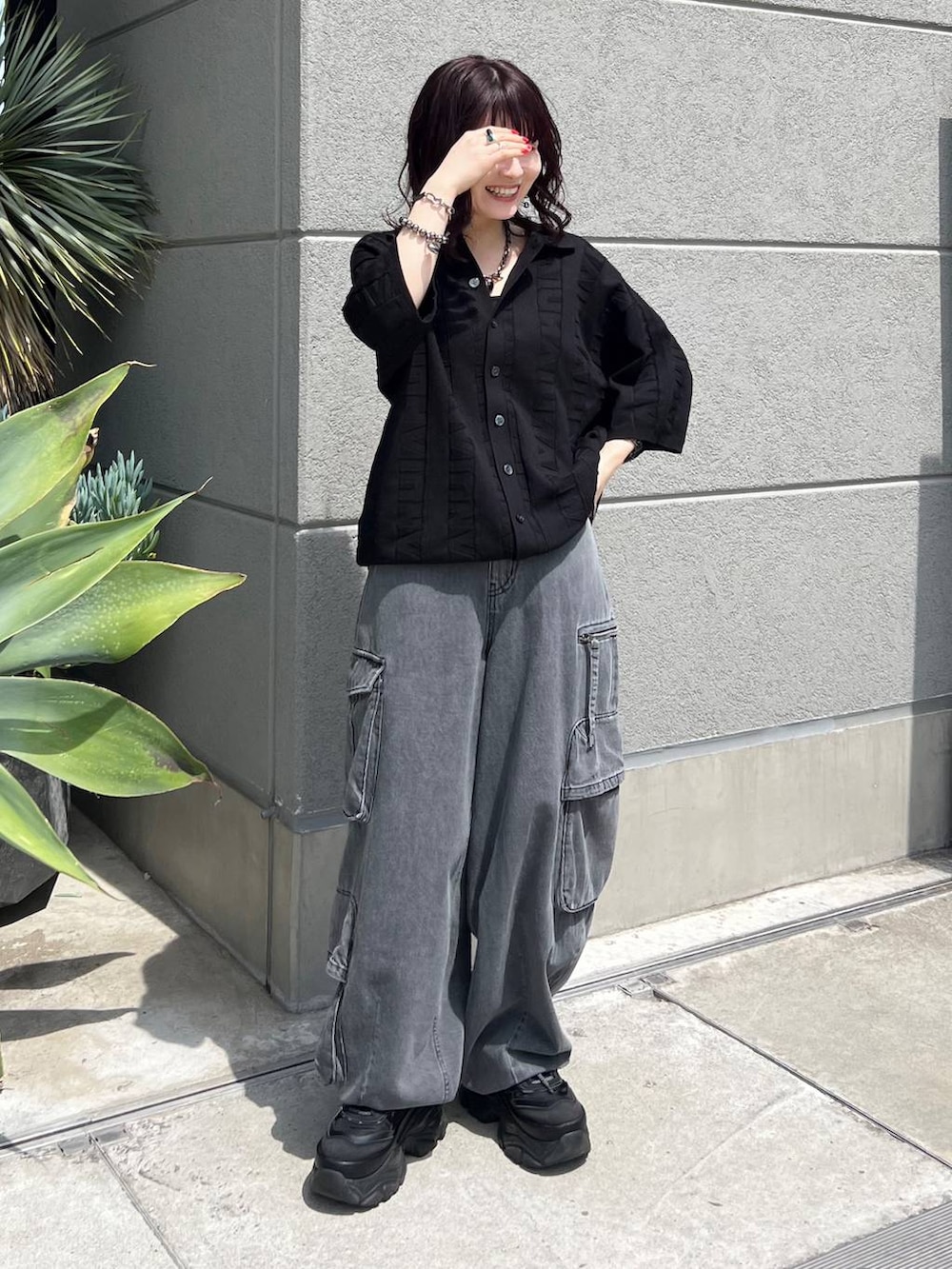 ブラック系のニット/セーター、ブラック系のスニーカー、ブラック系のデニムパンツを着用したレディースの夏コーディネートの2枚目の写真