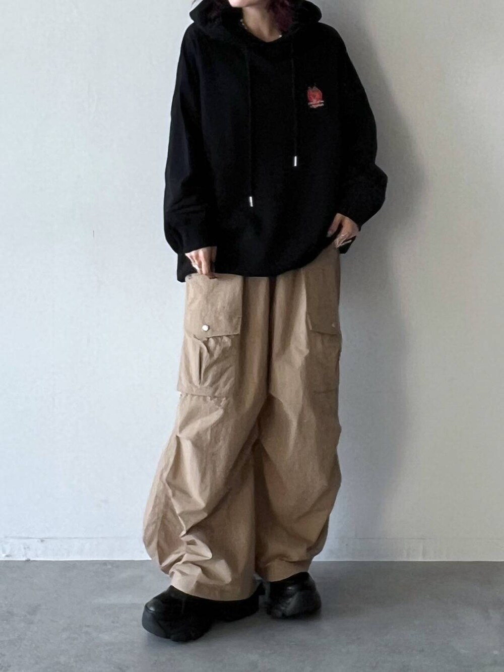 ブラック系のスニーカー、ベージュ系のカーゴパンツ、ブラック系のパーカーを着用したレディースの夏コーディネートの2枚目の写真