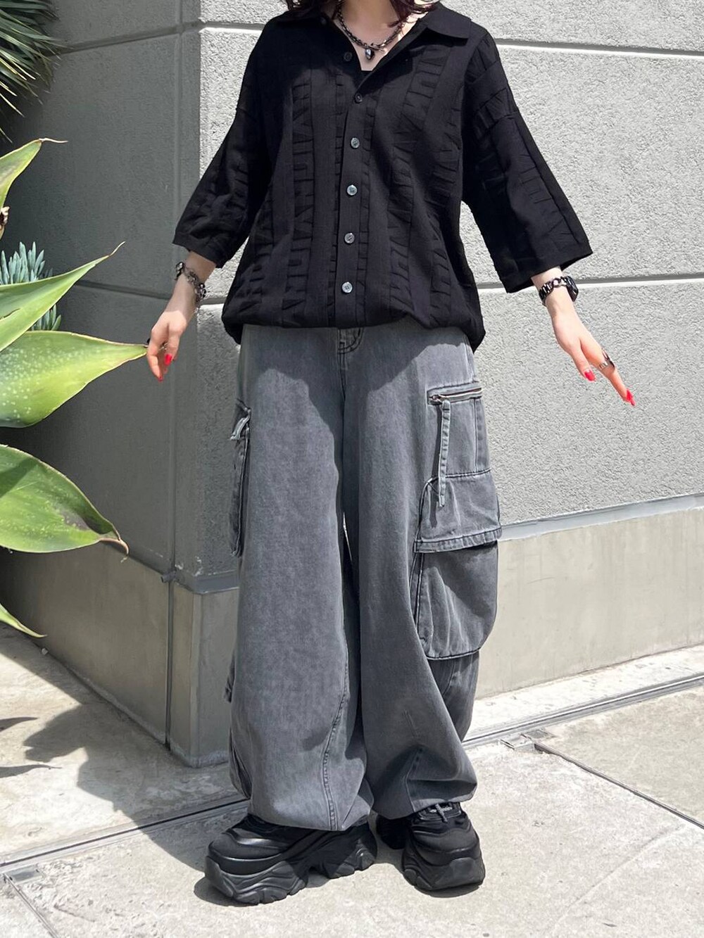 ブラック系のニット/セーター、ブラック系のスニーカー、ブラック系のデニムパンツを着用したレディースの夏コーディネートの6枚目の写真