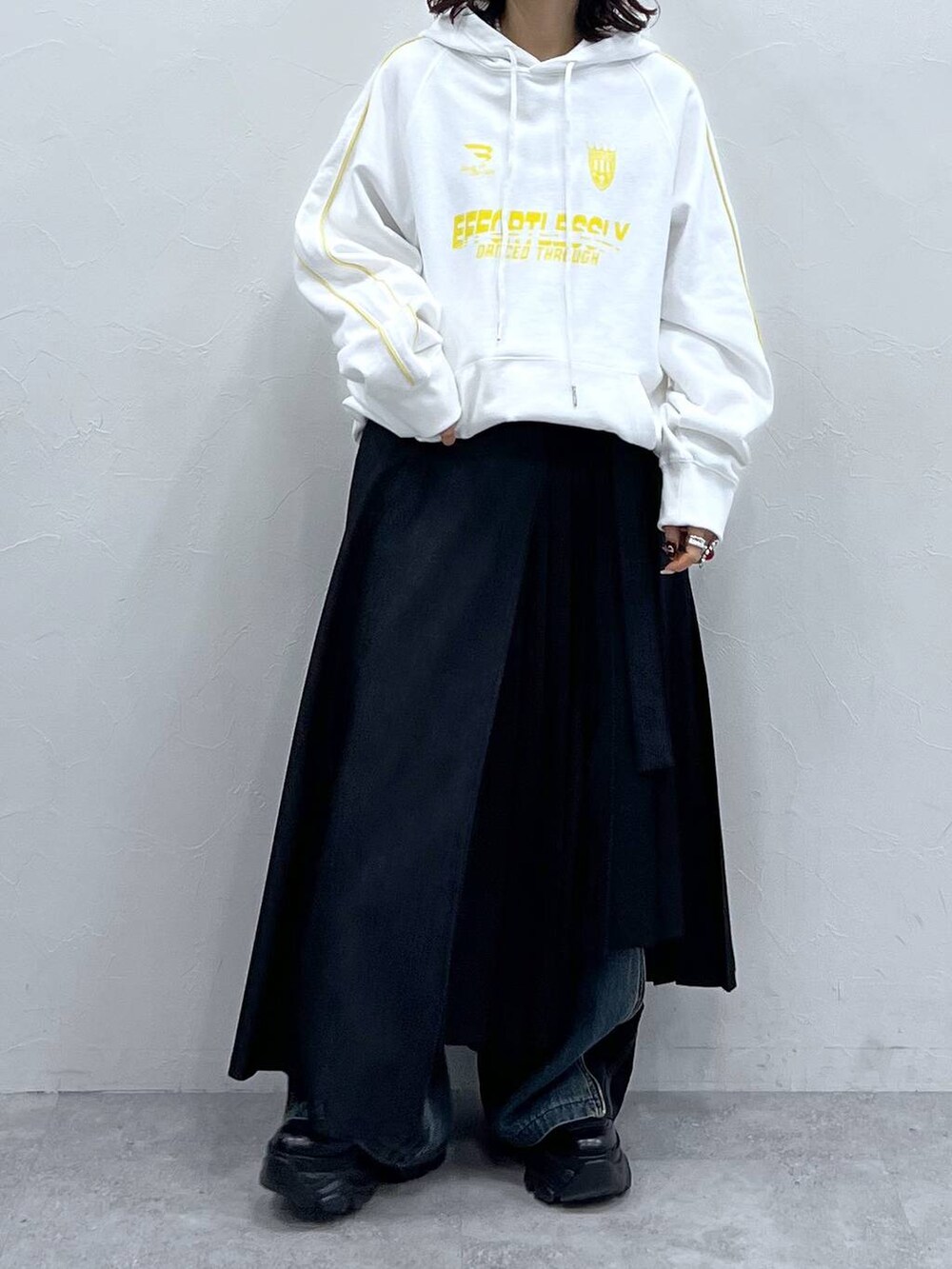 ブラック系のブーツ、ブルー系のデニムパンツ、ブラック系のスカートを着用したレディースの冬コーディネートの5枚目の写真