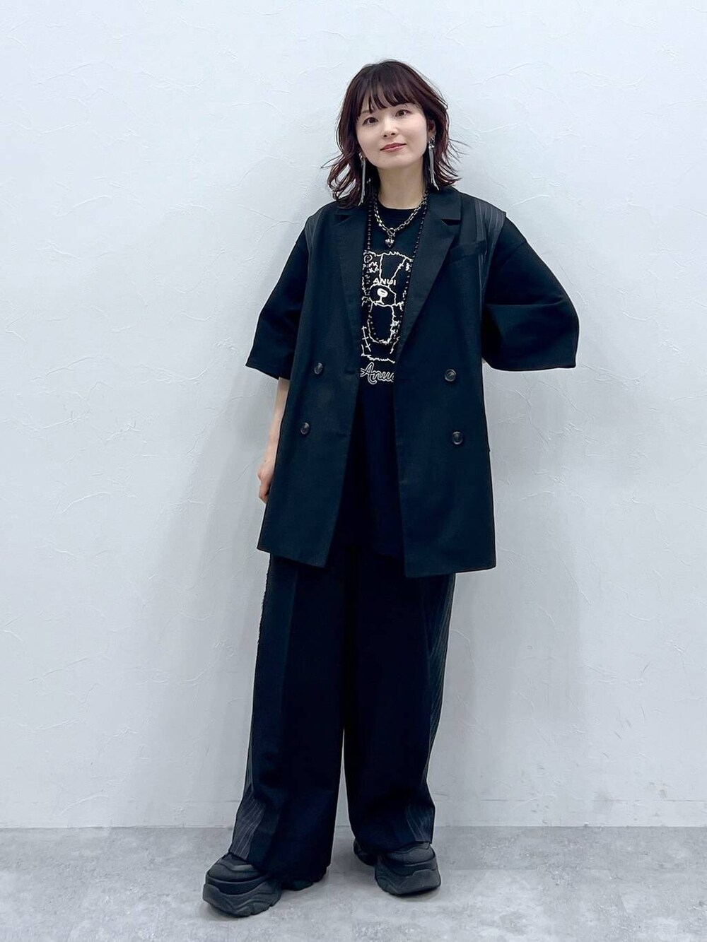 ブラック系のスラックス、ブラック系のTシャツ/カットソー、ブラック系のスニーカーを着用したレディースの春コーディネートの2枚目の写真