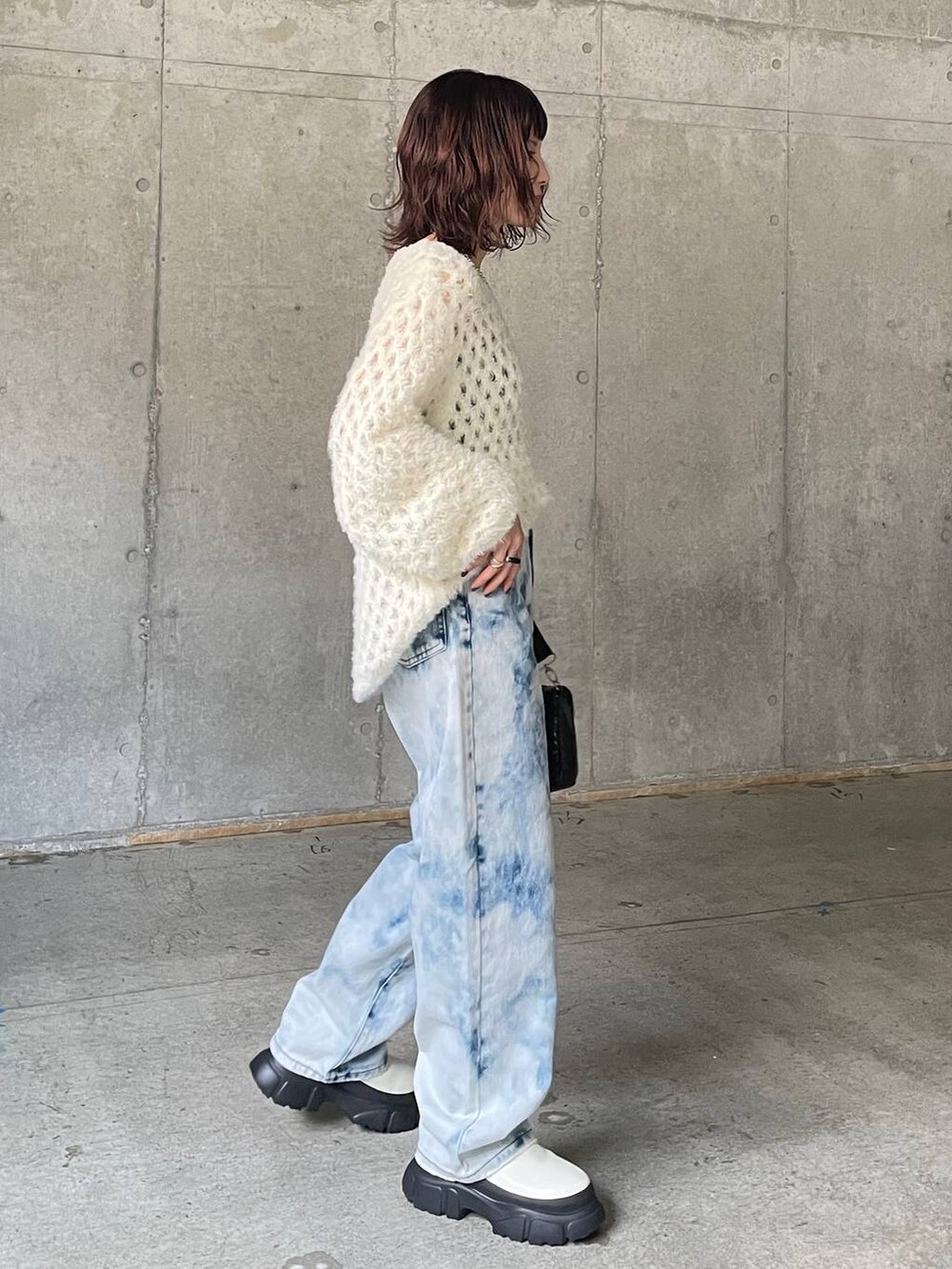 ブルー系のデニムパンツ、ホワイト系のブーツ、ホワイト系のニット/セーターを着用したレディースの秋コーディネートの3枚目の写真