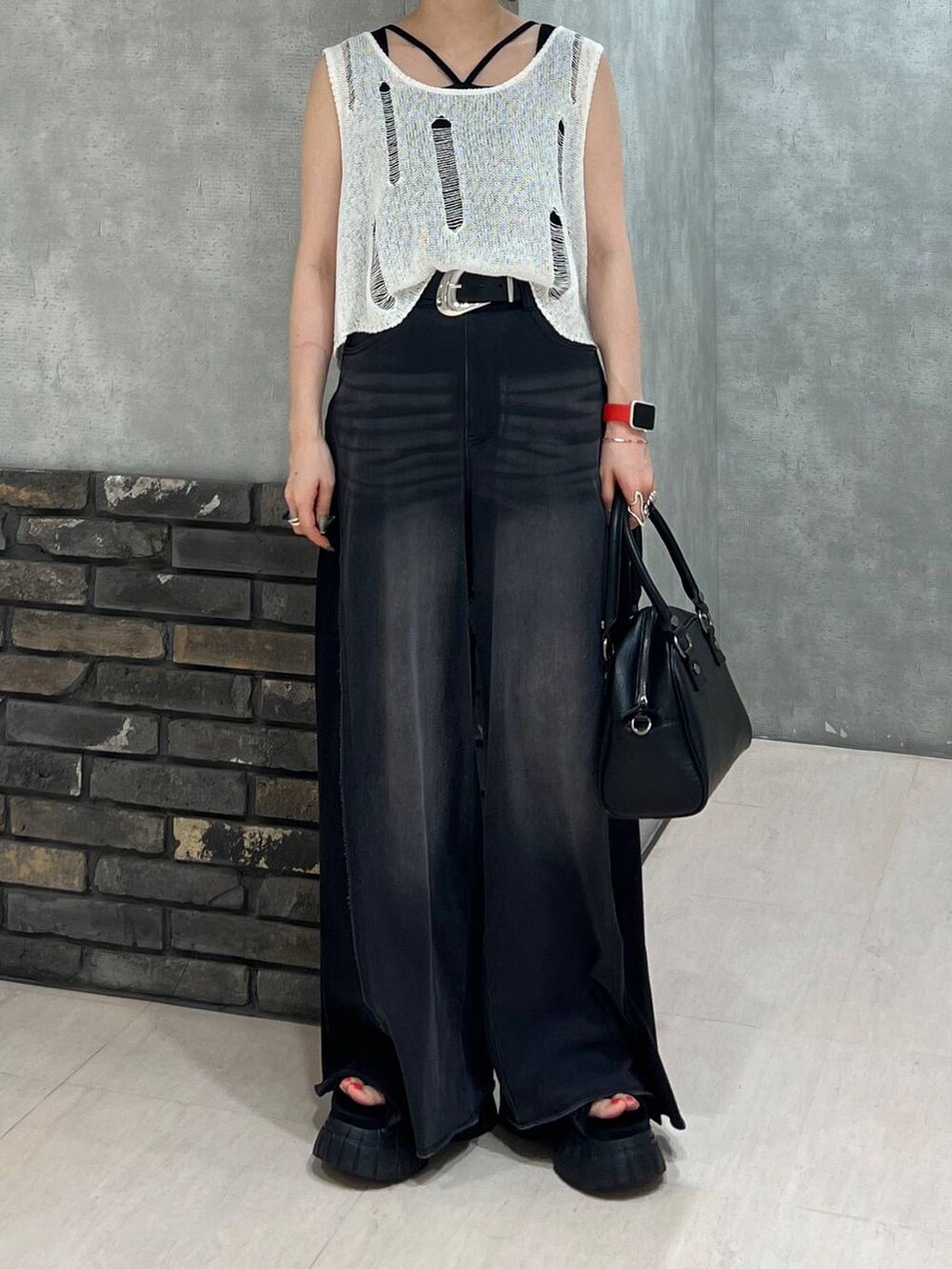 ブラック系のデニムパンツ、ブラック系のショルダーバッグ、ホワイト系のベストを着用したレディースの夏コーディネートの6枚目の写真