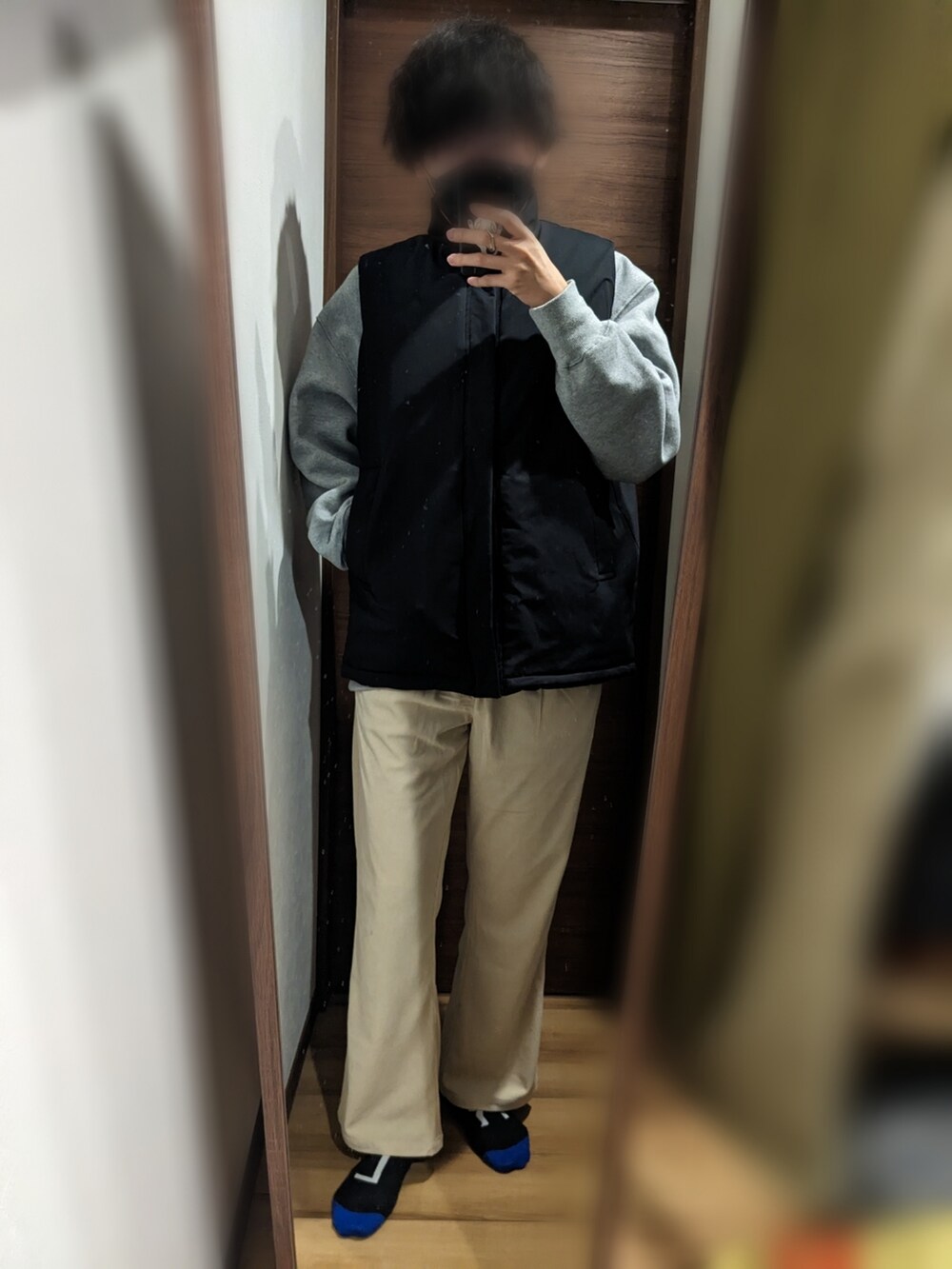 ブラック系のダウンベスト、グレー系のスウェット、ホワイト系のスラックスを着用したメンズの冬コーディネートの2枚目の写真