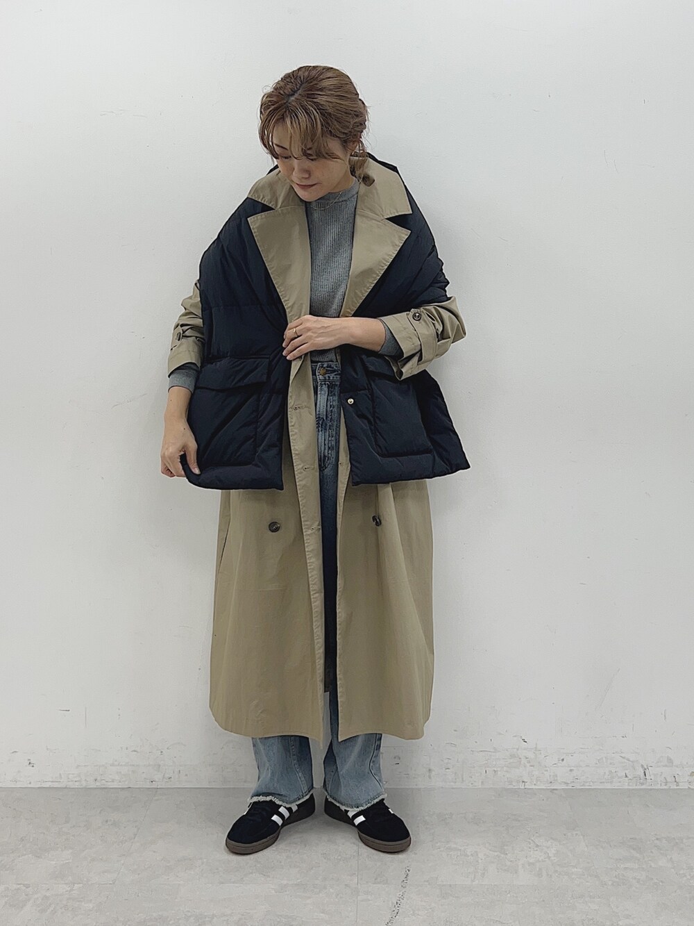ベージュ系のトレンチコート、ブルー系のデニムパンツ、ブラック系のストール/ショールを着用したレディースの秋コーディネートの2枚目の写真