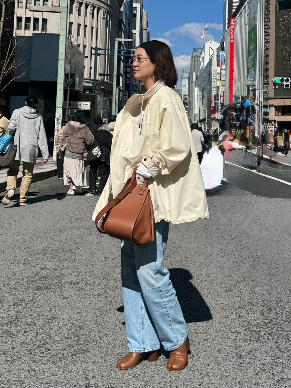 ホワイト系のミリタリージャケット、ブルー系のデニムパンツ、ブラウン系のブーツを着用したレディースの春コーディネートの2枚目の写真