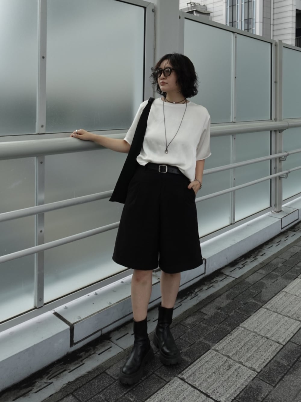 ホワイト系のトップス、ブラック系のパンツ、ブラック系のブーツを着用したレディースの秋コーディネートの2枚目の写真