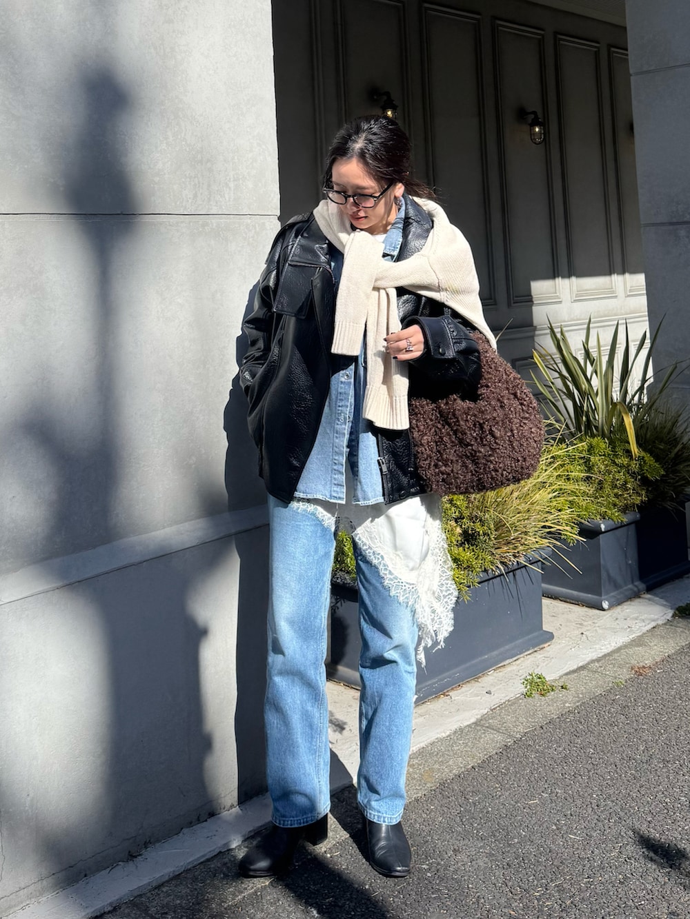 ブルー系のデニムパンツ、ブラック系のブーツ、ブラウン系のバッグを着用したレディースの冬コーディネートの3枚目の写真