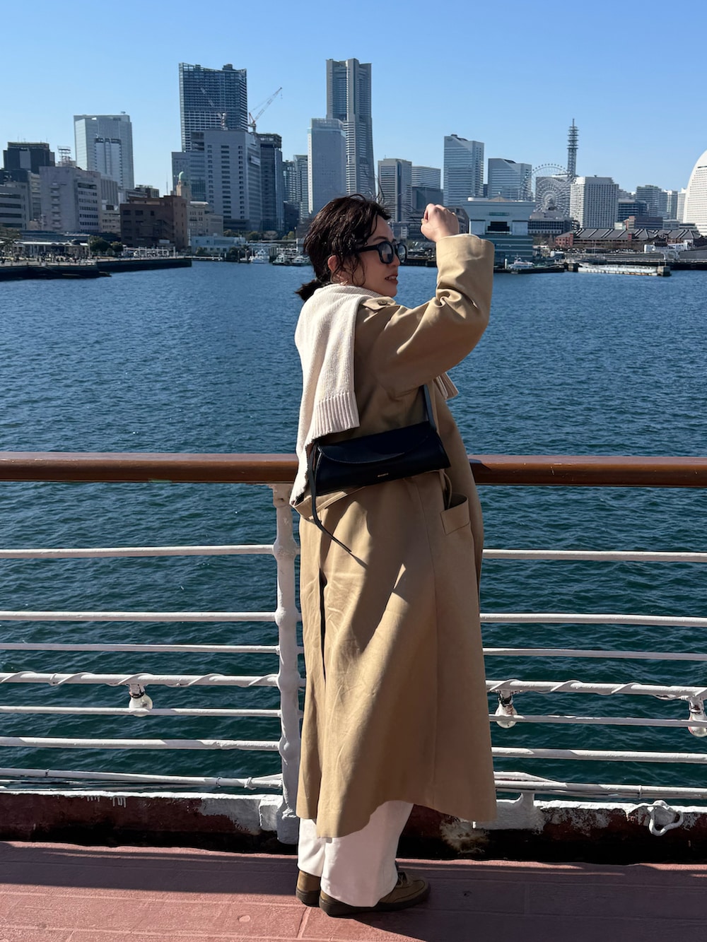 イエロー系のニット/セーター、ホワイト系のパンツ、ベージュ系のスニーカーを着用したレディースの春コーディネートの2枚目の写真