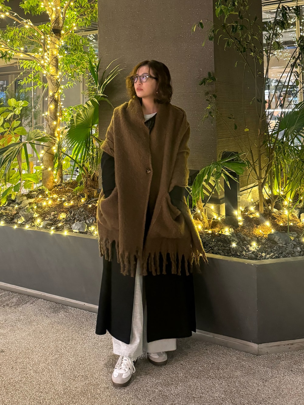 ブラック系のチェスターコート、グレー系のニット/セーター、ホワイト系のスニーカーを着用したレディースの冬コーディネートの2枚目の写真