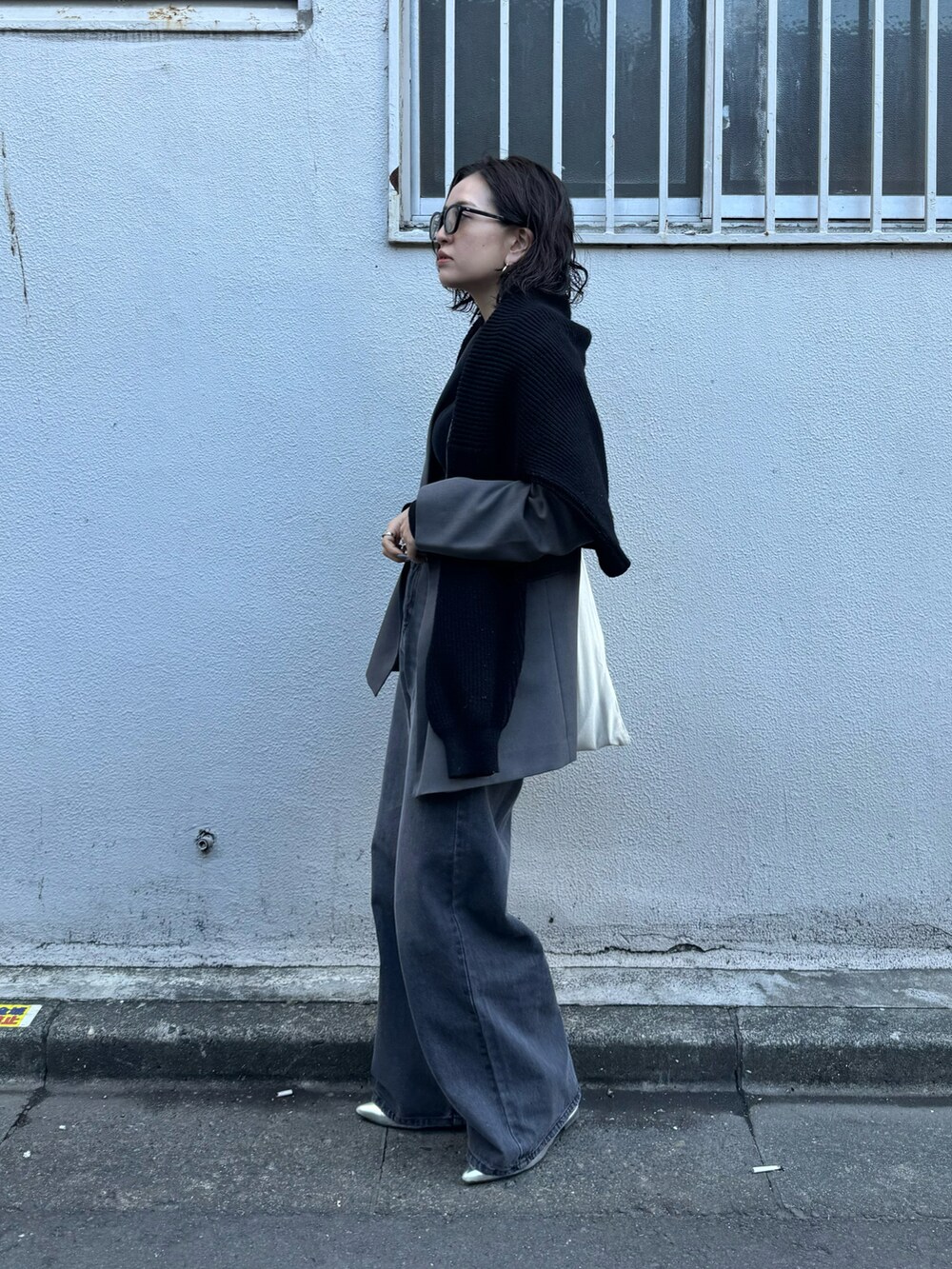 ブラック系のニット/セーター、ブラック系のデニムパンツ、シルバー系のシューズを着用したレディースの春コーディネートの2枚目の写真